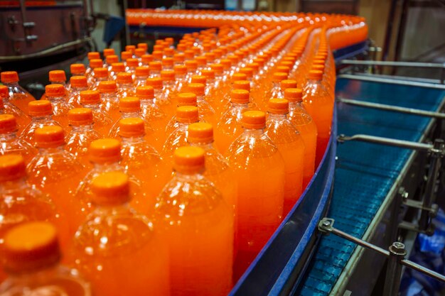 Transportador interior da fábrica de bebidas fluindo com garrafas para suco ou água