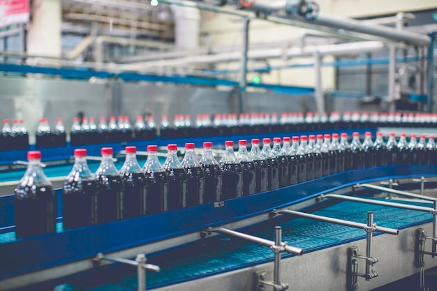 Transportador interior de la fábrica de bebidas que fluye con botellas de agua carbonatada