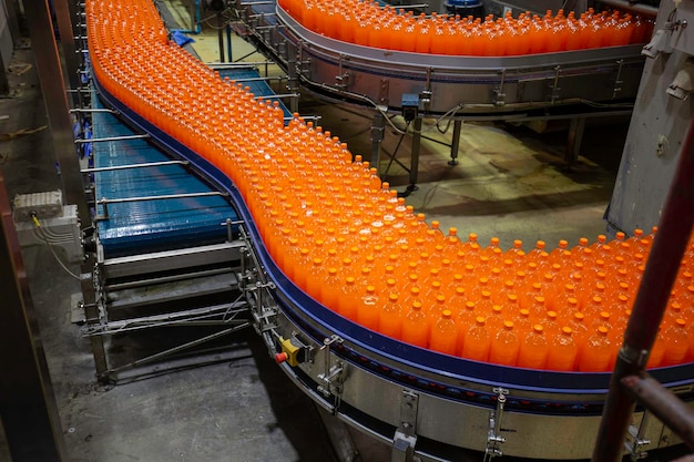 Transportador interior de la fábrica de bebidas que fluye con botellas de jugo