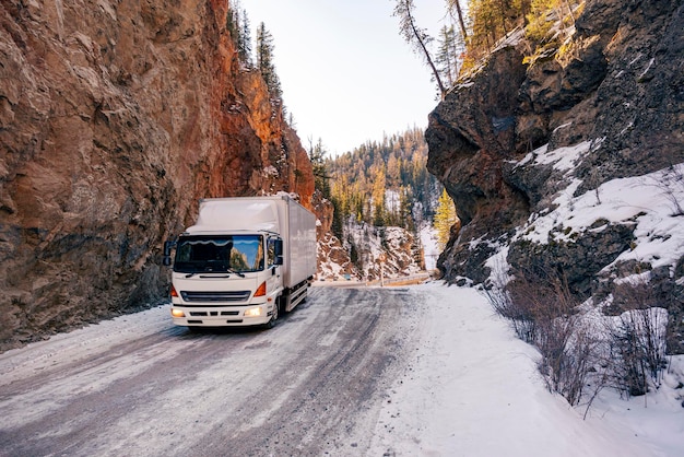 Transporte de cargas em condições difíceis. Passeios de caminhão em encosta nevada na floresta no inverno.