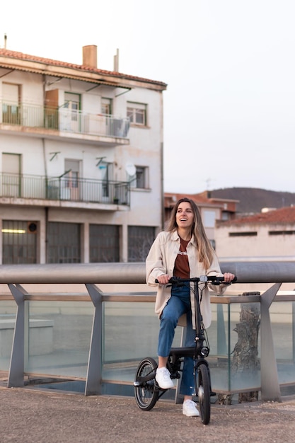 Transporte ecológico para a cidade Jovem sorridente andando de bicicleta elétrica com o prédio da cidade atrás