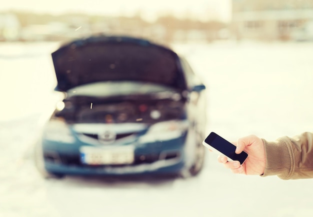 Foto transporte, invierno y concepto de vehículo - cierre de hombre con coche roto y smartphone