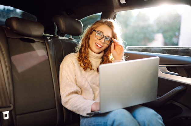 Transporte de negocios Mujer con computadora portátil trabaja en el asiento trasero del automóvil Concepto de transporte
