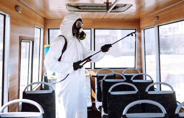 Transporte público de limpeza Homem em traje de proteção lavagem e desinfecção transporte público
