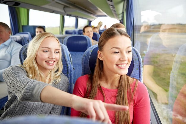 transporte, turismo, amistad, viaje por carretera y concepto de personas - mujeres jóvenes o amigas adolescentes que viajan en autobús de viaje