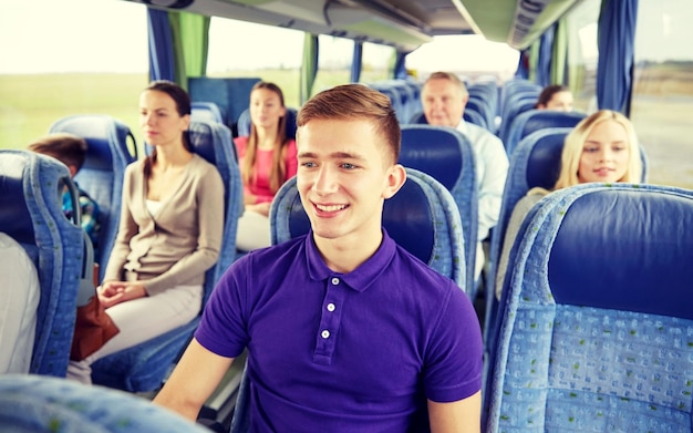 transporte, turismo, viagem e conceito de pessoas - jovem feliz sentado em ônibus ou trem de viagem