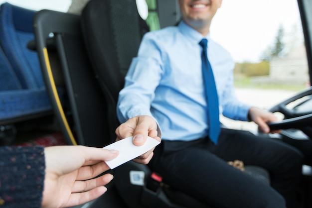 transporte, turismo, viagem rodoviária e conceito de pessoas - close-up de motorista de ônibus vendendo passagem para passageiro