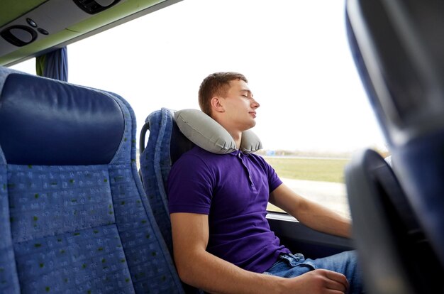 transporte, turismo, viaje por carretera, descanso y concepto de personas - joven feliz durmiendo en autobús de viaje con almohada inflable