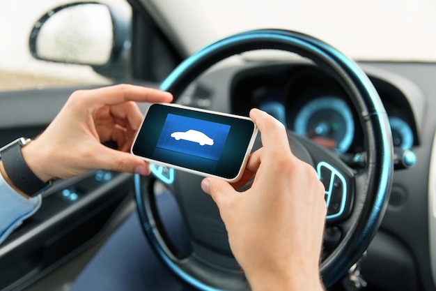 transporte, viagem de negócios, tecnologia e conceito de pessoas - close-up de mãos masculinas com ícone de carro na tela do smartphone no carro