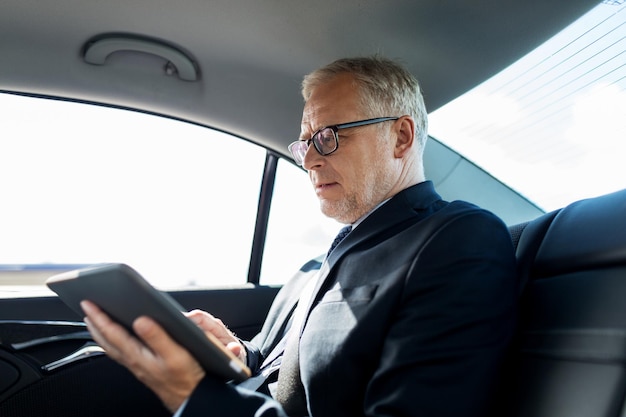 transporte, viaje de negocios, tecnología y concepto de personas - hombre de negocios senior con computadora de tablet pc conduciendo en el asiento trasero del camión