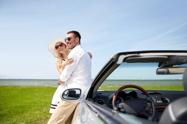 Foto transporte, viajes, amor, fecha y concepto de personas - hombre y mujer felices abrazándose cerca del camión cabriolet al lado del mar