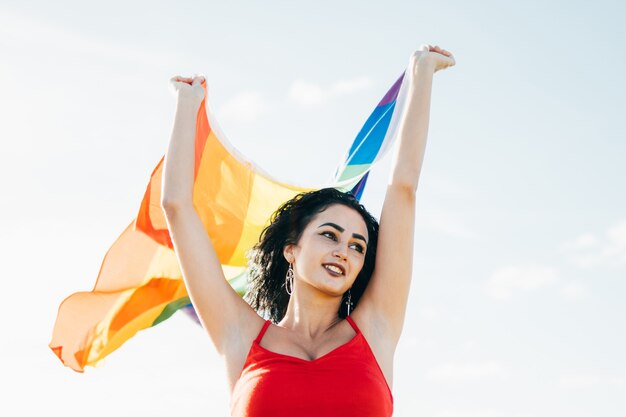 Transsexuelle Frauen tragen eine Gay-Pride-LGBT-Flagge, die sich an einem sonnigen Tag mit der Brise bewegt. Sie kämpft um sexuelle Freiheit.