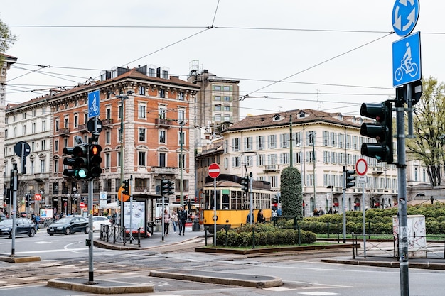 Tranvía amarillo viaja por la calle con el telón de fondo de edificios antiguos milán italia