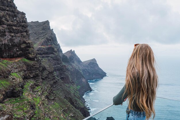 El trasero de una mujer de cabello rubio mirando el paisaje de la costa