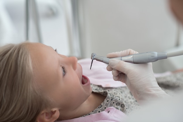 Tratamento de dentes. Uma criança loira fazendo tratamento dentário no dentista