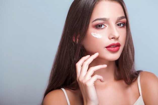 Foto tratamento de rosto. mulher com rosto saudável, aplicar creme cosmético sob os olhos