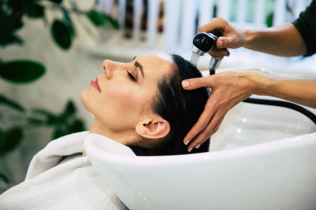 Tratamento de spa. Vista superior das mãos do cabeleireiro lavando o cabelo de sua cliente no salão antes do processo de penteado.