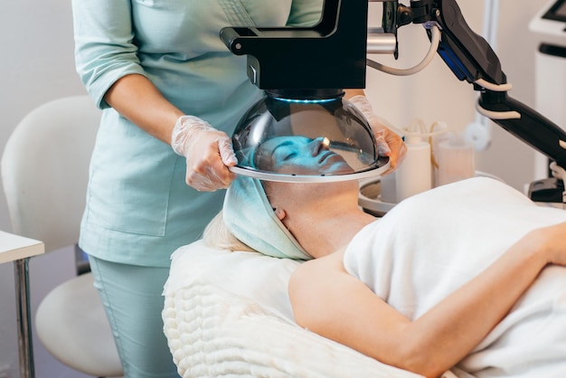 Tratamento de terapia facial com luz LED para mulheres adultas na clínica moderna de cosmetologia