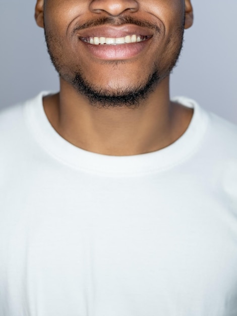 Tratamento dentário Saúde bucal Higiene bucal Retrato de homem africano bonito alegre em camiseta branca sorrindo isolado em fundo cinza