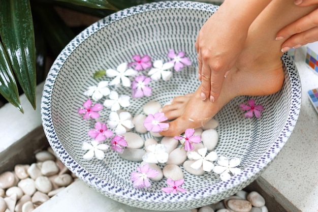 Tratamento e produto spa para mulher feeta. Banho de pés em uma tigela com flores tropicais, Tailândia. Conceito Saudável.