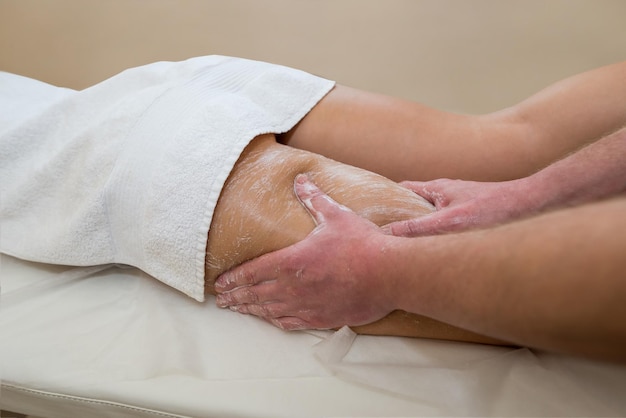 Tratamentos de beleza no spa. Massagista aplicando esfoliante nas pernas da garota. Esfregar as pernas no spa.