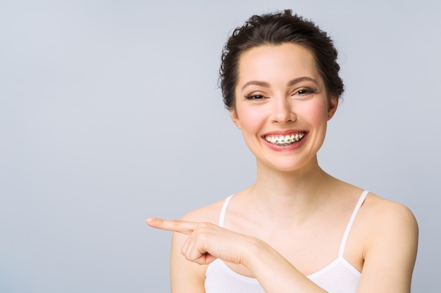 Tratamiento de ortodoncia. Concepto de cuidado dental. Hermosa mujer sana sonrisa de cerca. Primeros soportes de cerámica y metal en los dientes. Hermosa sonrisa femenina con tirantes.