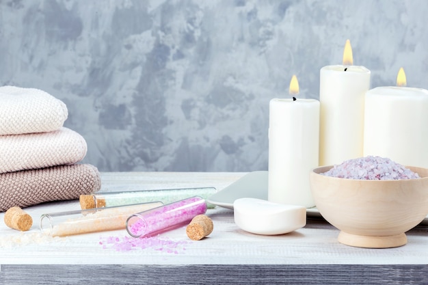 Tratamiento de spa de belleza con velas, sal y toallas contra un fondo gris con espacio de copia.