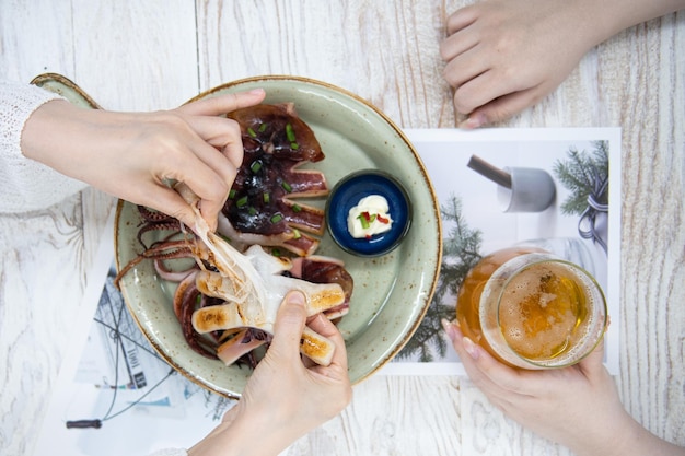 Tratando de comer calamares a la parrilla y cerveza en la mesa.