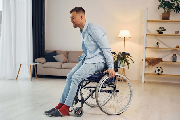 Tratando de moverse El hombre discapacitado en silla de ruedas está en casa