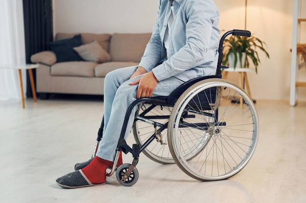Tratando de moverse El hombre discapacitado en silla de ruedas está en casa