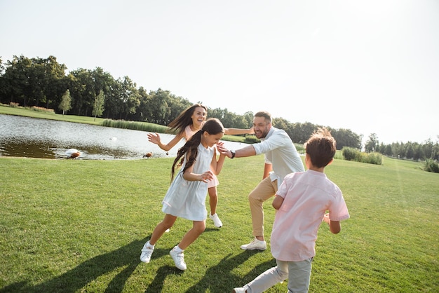 Trate de atraparme familia joven feliz jugando y sonriendo mientras paso el tiempo libre con