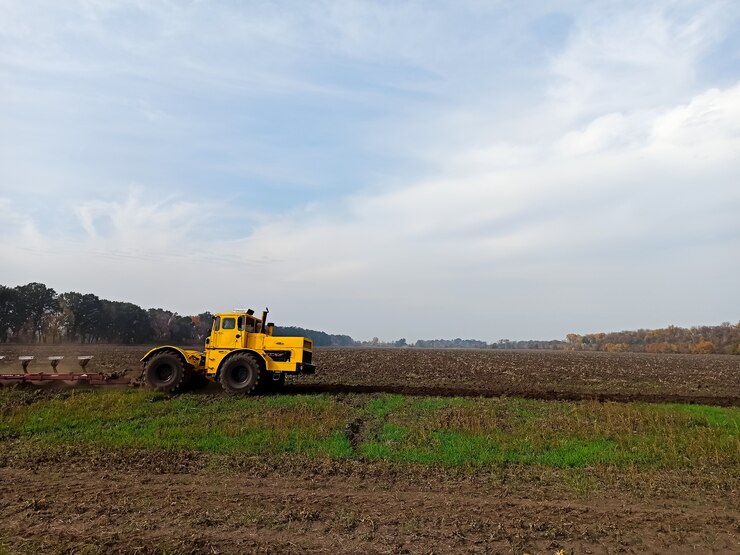 Foto trator agrícola amarelo, combine passeios no campo, manuseia o solo, arado grita com o solo no outono.