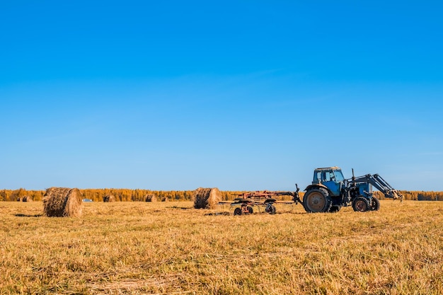 Trator coletando palheiros em um campo