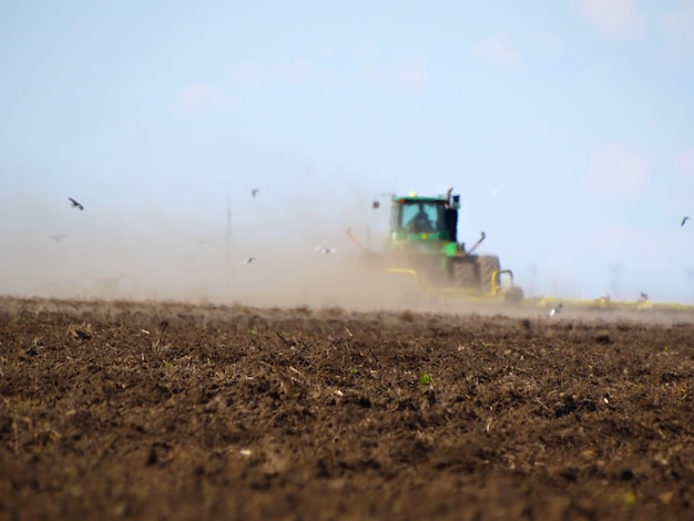 Trator cultivando campo em obras de primavera