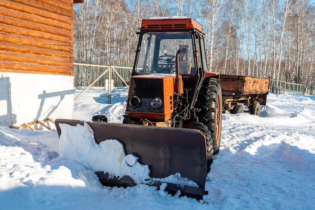 Trator de arado de neve com rodas laranja com lâmina no inverno