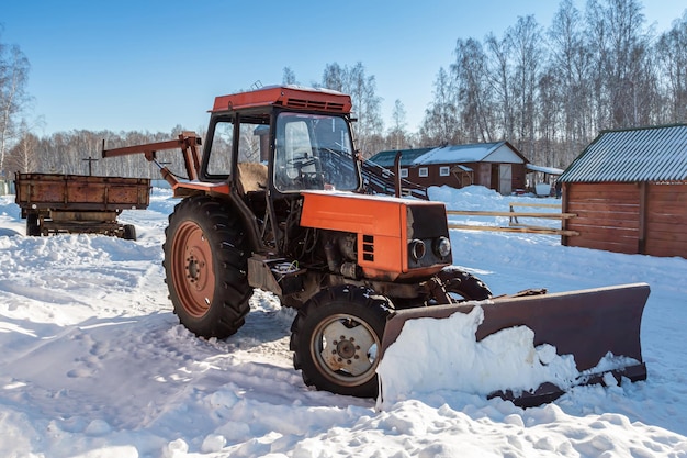 Trator de arado de neve com rodas laranja com lâmina no inverno