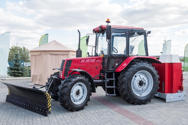 Foto trator de rodas vermelho com aiveca em uma feira agrícola