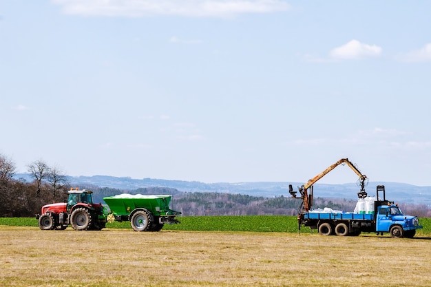 Trator espalhando fertilizante no campo de grama. trabalho agrícola.