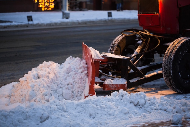 Trator limpando a estrada da neve. a escavadeira limpa as ruas de grandes quantidades de neve na cidade.
