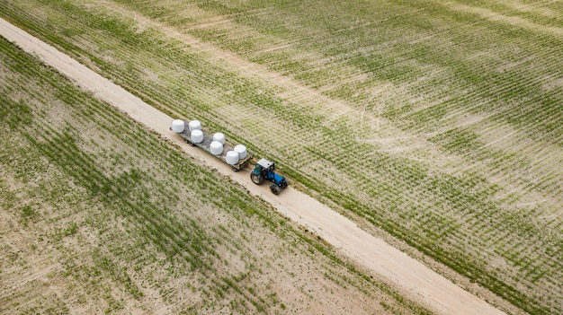 Trator monta no campo e carrega fardos de vista aérea do feno