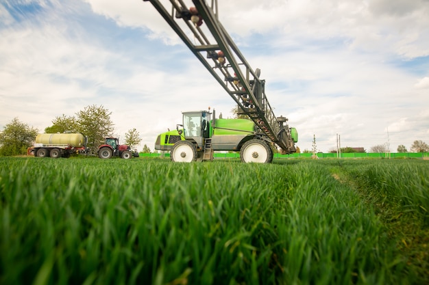 Trator pulverizando pesticidas, fertilizando no campo vegetal com pulverizador na primavera, conceito de fertilização