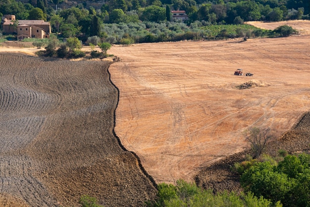 Trator trabalhando na paisagem rural de terras agrícolas na Toscana Itália