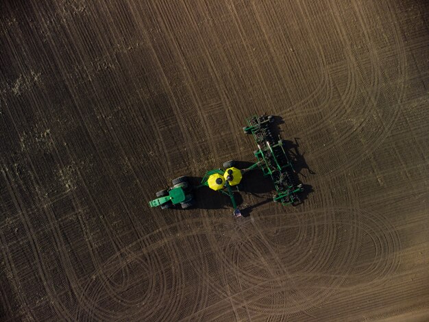 Trator verde com complexo de semeadura na vista do campo de cima