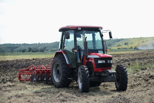 Trator vermelho brandnew no funcionamento de campo. Trator cultivando o solo e preparando um campo para o plantio