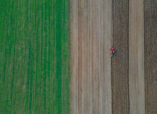 Trator vermelho com em um campo para arar a vista aérea do campo agrícola