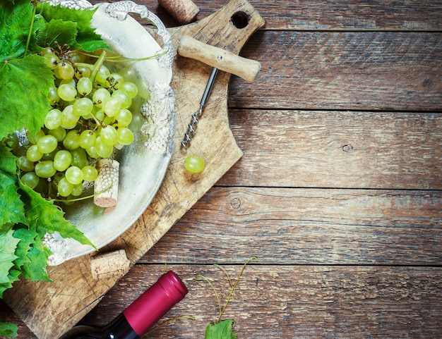 Trauben, eine Flasche Wein, Korken und Korkenzieher auf einer hölzernen alten Tabelle, rustikale Art