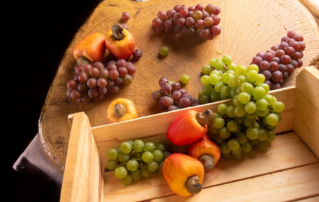 Trauben in einer Holzkiste und Cashewnüsse mit Stoffen im Hintergrund, geringe Schärfentiefe