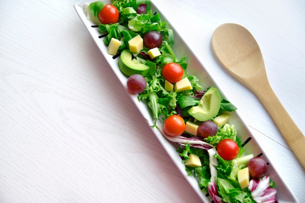 Foto traubensalat mit tomate und avocado mit hölzernem löffel