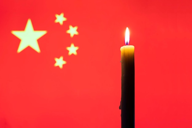 Trauer im Land brennende Kerze auf dem Hintergrund der chinesischen Flagge Opfer der Katastrophe oder des Kriegskonzepts Gedenktag Gedenktag Nationale Trauer