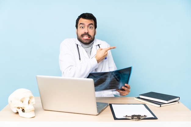 Foto traumatologista profissional no local de trabalho assustado e apontando para o lado